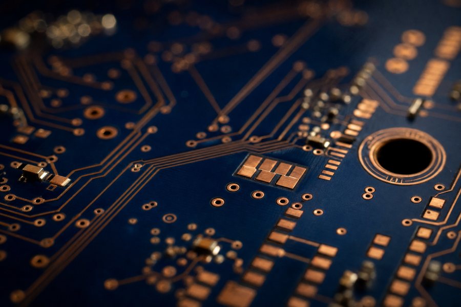 Macro photograph of a deep blue circuit board with copper traces