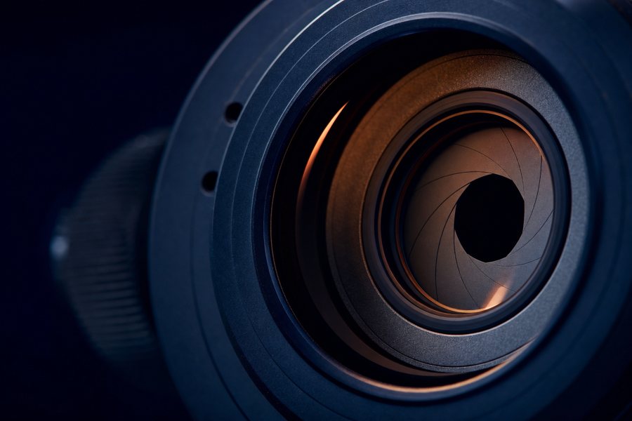 Macro photograph of an optical lens aperture in deep blue with copper reflections